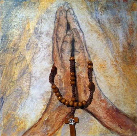 Painted praying hands in ochre and sepia tones with a real brown wooden rosary and cross draped over them